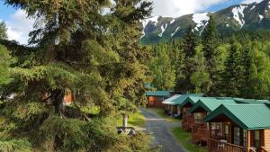 a row of cabins in a forest with mountains at Gwin's Lodge & Roadhouse in Cooper Landing
