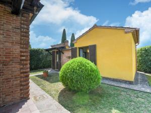 una casa amarilla con un arbusto delante de ella en Belvilla by OYO Chiaradue, en Acquaviva
