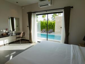 a bedroom with a bed and a view of a pool at Toledo Pool Villa in Nakhon Si Thammarat
