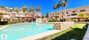 ein Swimmingpool vor einem Gebäude mit Palmen in der Unterkunft Jardines de Montemar in Benissa