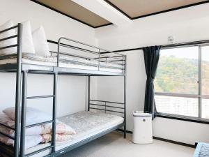 a bedroom with two bunk beds and a window at Guest House YAMATOSO in Ito