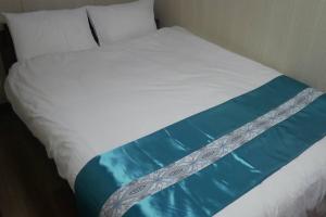 Cama blanca con sábanas y almohadas azules y blancas en 民泊 桔梗 en Awaji