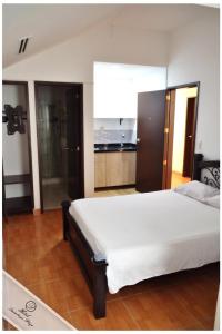 a bedroom with a large white bed and a kitchen at Hotel Quimbaya Plaza in Quimbaya