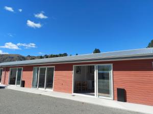 a red building with sliding glass doors at LAKE ESCAPE - Brand new warm and quiet two bedroom Apartment in Otematata
