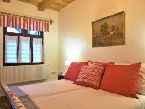 a bedroom with a bed with red pillows at Dura Guesthouse, Garden Wellness Retreat near the Tisza River in Paszab +2 photos