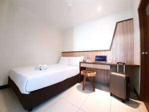 a hotel room with a bed and a suitcase at Hotel Pantes Kota Lama Semarang in Semarang