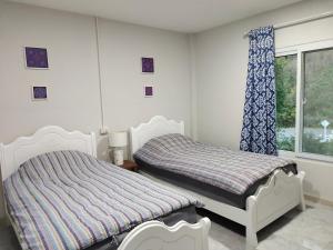 1 dormitorio con 2 camas y ventana en The Blue Rim Vacation Cottage Khao Yai, en Pak Chong