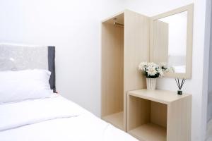 Apartemen Gunung Putri Square by Sirooms في بوغور: غرفة نوم بيضاء مع مرآة وسرير