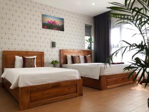 a bedroom with two beds and a potted plant at Heritage Hotel in Tuy Hoa