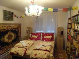a bedroom with a bed with red pillows and a chandelier at Thomas Apartman Eger in Eger