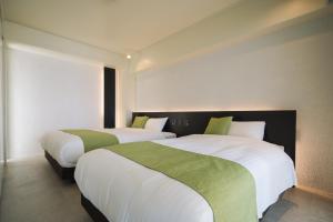 two beds in a hotel room with white and green sheets at KEN KEN VILLA YUUMODORO in Motobu +28 photos