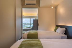 ein Hotelzimmer mit 2 Betten und einem Balkon in der Unterkunft KEN KEN VILLA YUUMODORO in Motobu + 29 Fotos