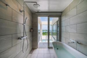 a bathroom with a bath tub and a window at KEN KEN VILLA YUUMODORO in Motobu