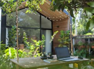 a laptop computer sitting on a wooden table in a garden at Moon Garden Homestay - cozy cabin and natural pool in Tay Ninh in Tây Ninh
