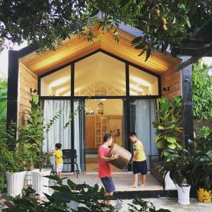 a man and two boys standing in front of a house at Moon Garden Homestay - cozy cabin and natural pool in Tay Ninh in Tây Ninh