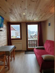 sala de estar con sofá rojo y 2 ventanas en Le Bois Joli en Saint-Pierre-de-Chartreuse