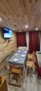 uma sala de jantar com mesa e cadeiras e uma televisão em Le Bois Joli em Saint-Pierre-de-Chartreuse