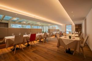 une salle à manger avec tables, chaises et fenêtres dans l'établissement Residence Hotel Eden - Family & Wellness Resort, à Andalo