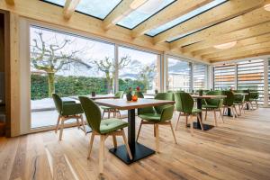 comedor con mesas y sillas y ventanas grandes en Residence Hotel Eden - Family & Wellness Resort en Andalo