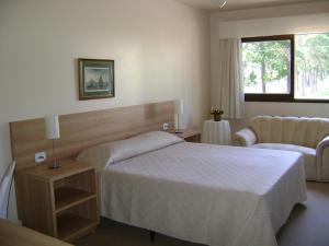 a hotel room with a bed and a couch at Hotel Areias Brancas in Rosário do Sul