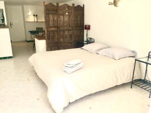 een wit bed met twee handdoeken erop bij Les flamants roses in Roussillon
