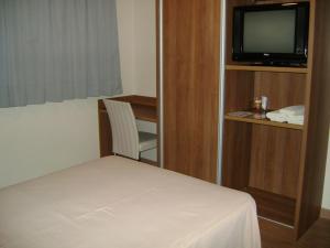 a hotel room with a bed and a television at Hotel Areias Brancas in Rosário do Sul