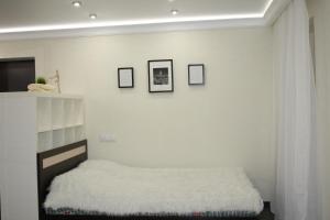 a white bedroom with a bed and some pictures on the wall at Art Apartments in Volgograd