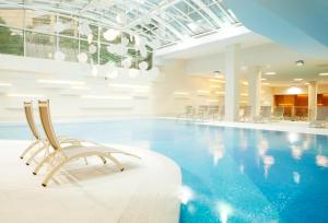 - une piscine avec des chaises dans un bâtiment dans l'établissement Wellness Hotel Apollo – Terme & Wellness LifeClass, à Portorož