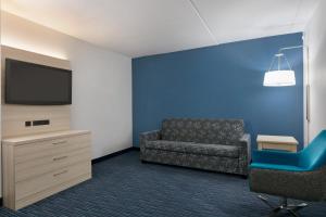 ein Wartezimmer mit einem Sofa und einem TV in der Unterkunft Holiday Inn Express Hotel & Suites Norfolk Airport, an IHG Hotel in Norfolk