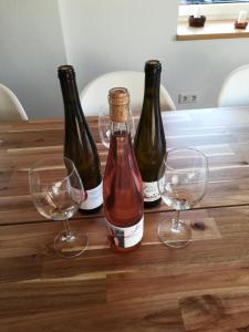 three bottles of wine and two glasses on a wooden table at Präsenzhof Lay in Lay