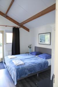 a bedroom with a large bed with blue sheets at Vakantiewoning 114 in villapark de oesterbaai in Wemeldinge