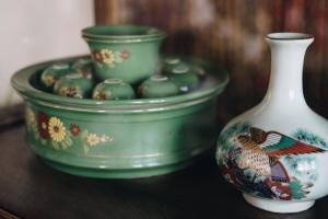 2 bols verts et un vase blanc sur une table dans l'établissement Sleeper House, à Trang