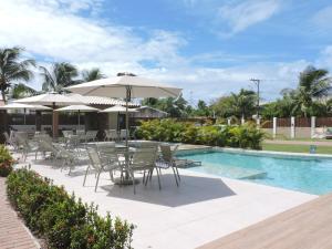 a pool with chairs and tables and umbrellas at Itacimirim - Village na Praia da Espera in Itacimirim
