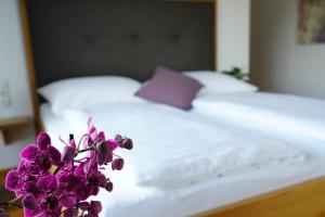 Una cama con sábanas blancas y flores púrpuras. en Walters Weinquartier, en Eisenberg an der Pinka