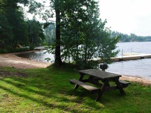 uma mesa de piquenique na relva ao lado de um lago em Two-Bedroom Holiday home in Håcksvik 2 em Håcksvik