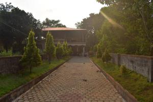 a cobblestone walkway in a park with trees and a building at Reunion Villa Abode in Udupi