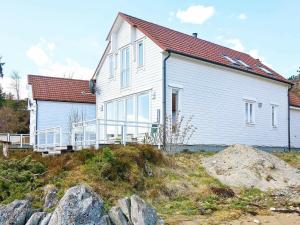 uma casa branca no topo de uma colina com pedras em Four-Bedroom Holiday home in Gurskøy 1 em Kjellsund