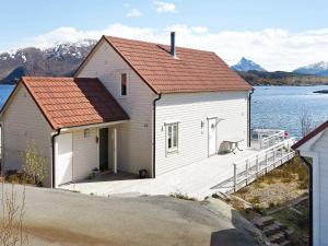 una casa bianca con un tetto rosso accanto a un corpo d'acqua di Four-Bedroom Holiday home in Gurskøy 1 a Kjellsund
