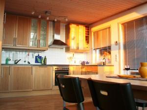 een keuken met houten kasten en een tafel met stoelen bij Four-Bedroom Holiday home in Sirevåg in Sirevåg