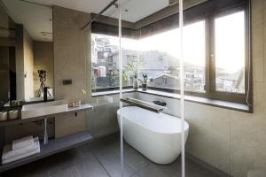 ein Bad mit einer Badewanne, einem Waschbecken und einem Fenster in der Unterkunft Jiufen 35 in Jiufen