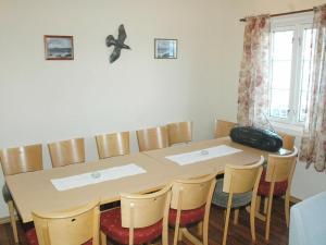 a dining room table with chairs and a suitcase on the wall at Two-Bedroom Holiday home in Lauvstad 1 in Lauvstad