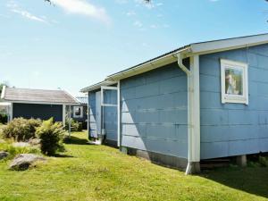 a blue house with a window and a yard at 6 person holiday home in FALKENBERG in Falkenberg