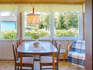 a dining room with a table and chairs and windows at 6 person holiday home in FALKENBERG in Falkenberg