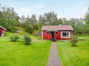 una pequeña casa roja en un patio de césped en 4 person holiday home in HEN N en Nösund