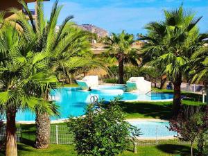 een zwembad met palmbomen in een resort bij Luxury Apartment 1st line Javea Arenal Beach in Jávea