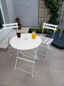 Twee stoelen en een witte tafel met twee drankjes erop. bij Modern & Cozy Studio w/ Backyard Near City Center in Limassol
