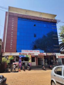 duży niebieski budynek z motocyklami zaparkowanymi przed nim w obiekcie Dharwad Residency w mieście Dharwad