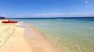 a beach with a red boat in the water at Casa al mare in San Pietro in Bevagna