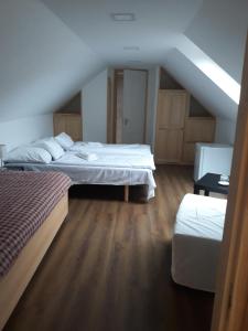 un dormitorio en el ático con 2 camas y una escalera en Zempléni Pitvaros Pihenő en Telkibánya
