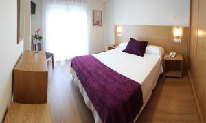 a hotel room with a large bed with a purple blanket at Hotel Brisa del Mar in O Grove